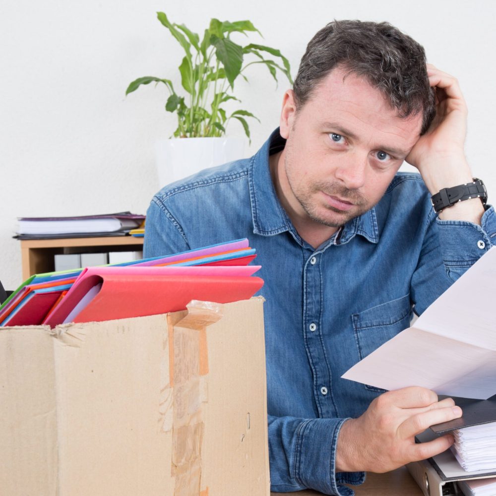 Sad man reading a dismiss notification, preparing his box