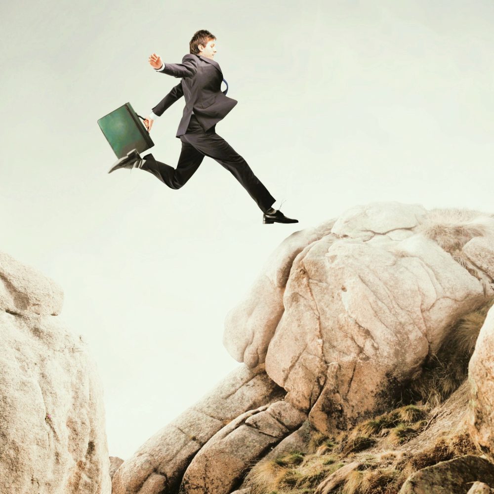 Obstacle | Businessman jumping from a rock to another